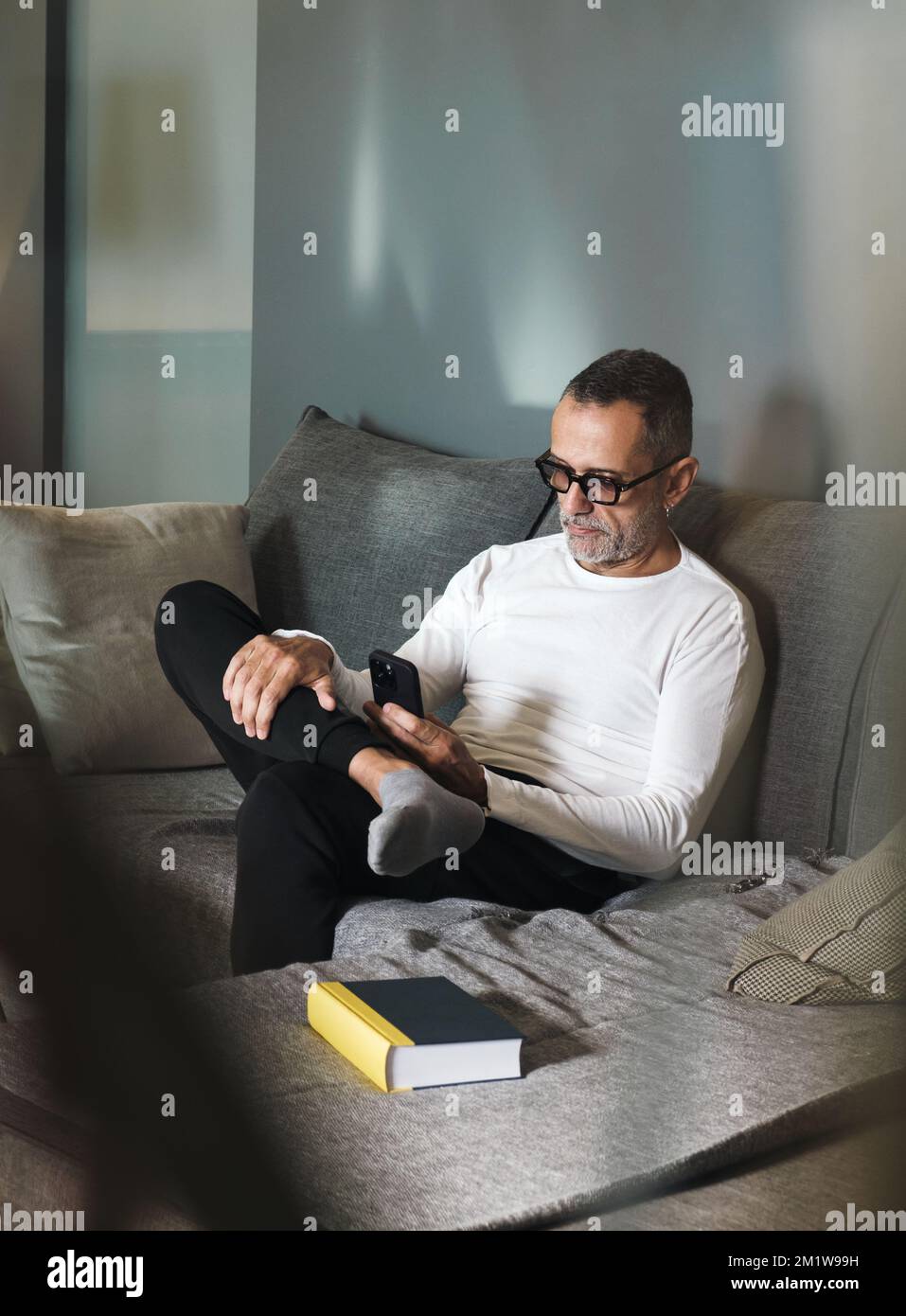 Man on couch with smartphone. Stock Photo