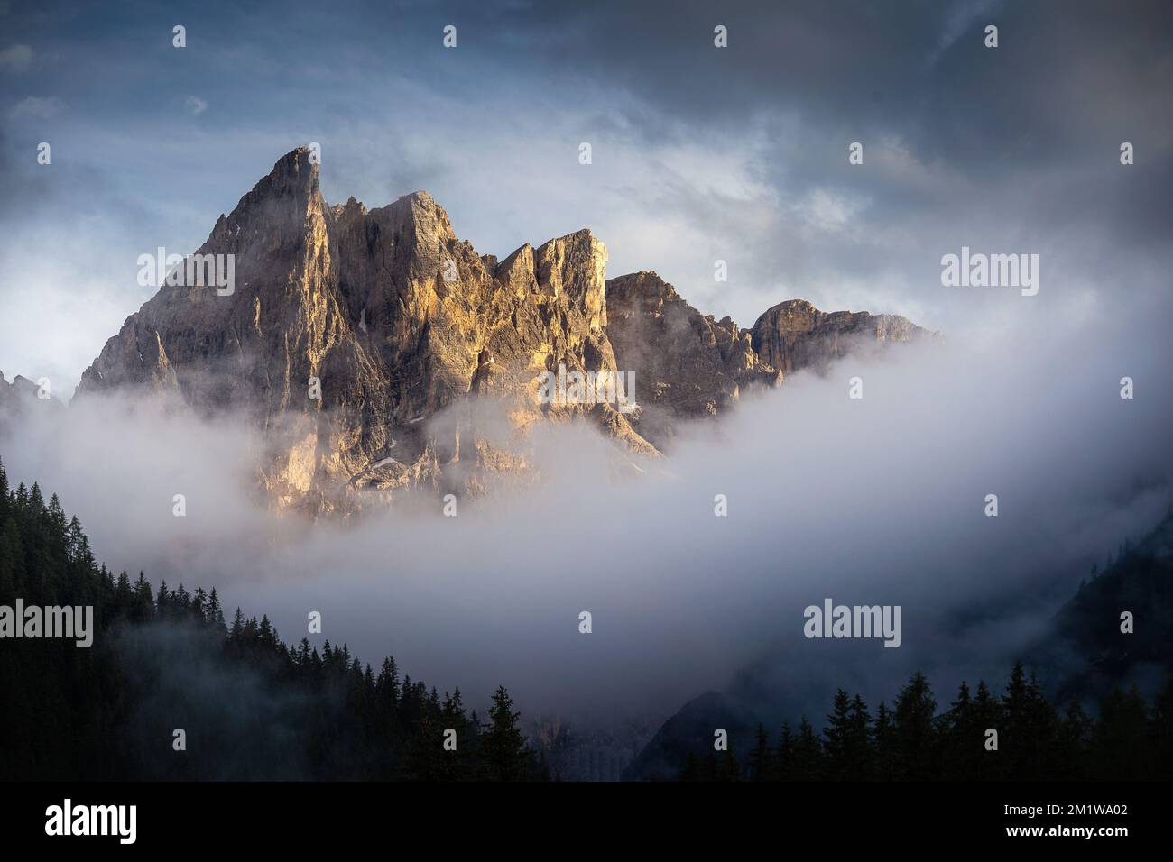 A breathtaking landscape of a rocky mountain covered in fog with a ...