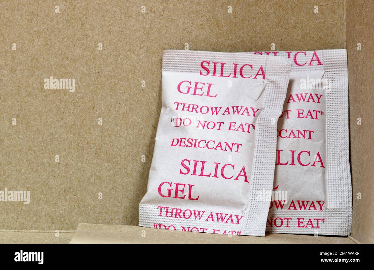 Two Silica gel packets in the bottom corner of a cardboard box. Porous