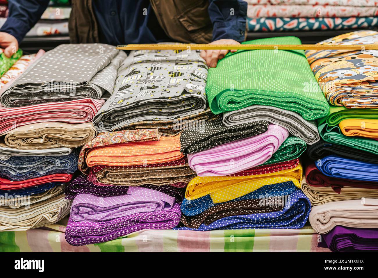 Colorful fabric rolls on counter of textile shop. Hands of salesman working at textile shop. . Selective focus Stock Photo