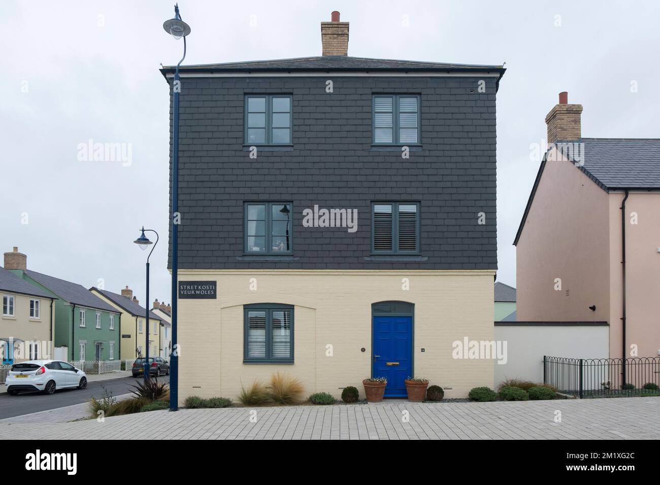 A cream, three storey, detached house with hanging tile cladding, in