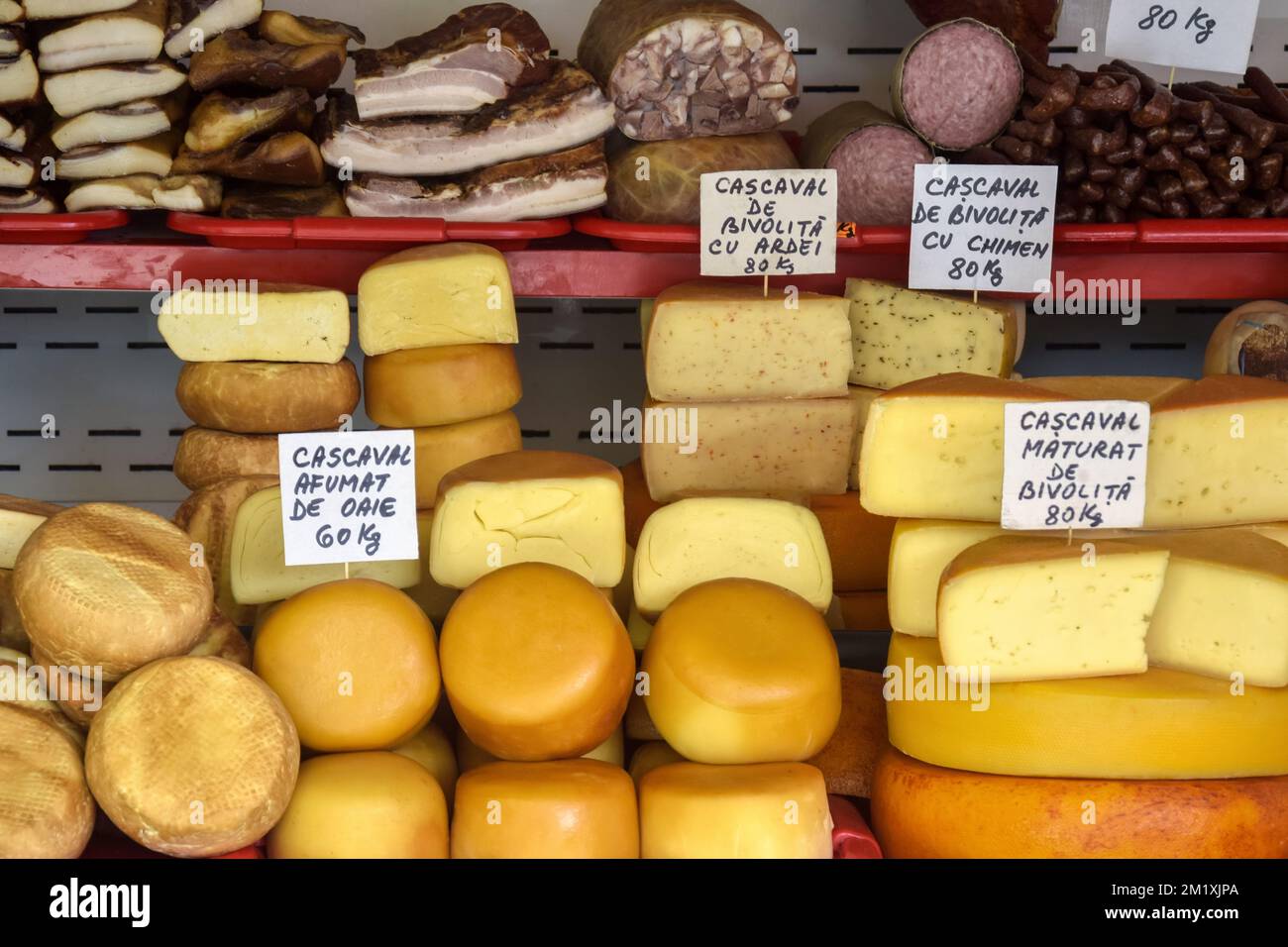 Cheese heads of different colors and sizes are stacked on counter