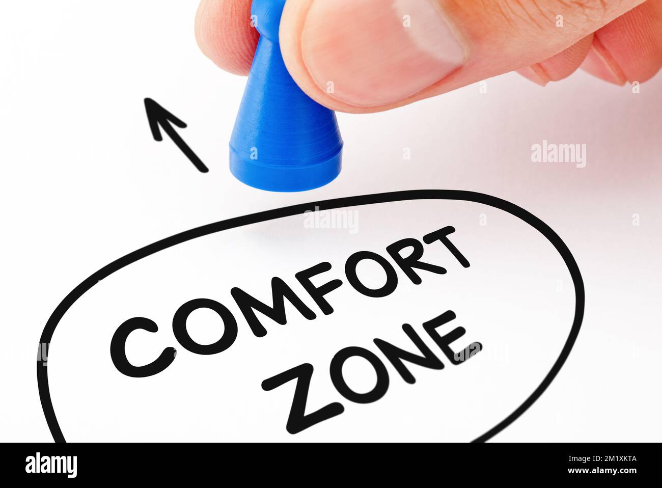 Hand moving a blue pawn out of a circle with text comfort zone. Concept