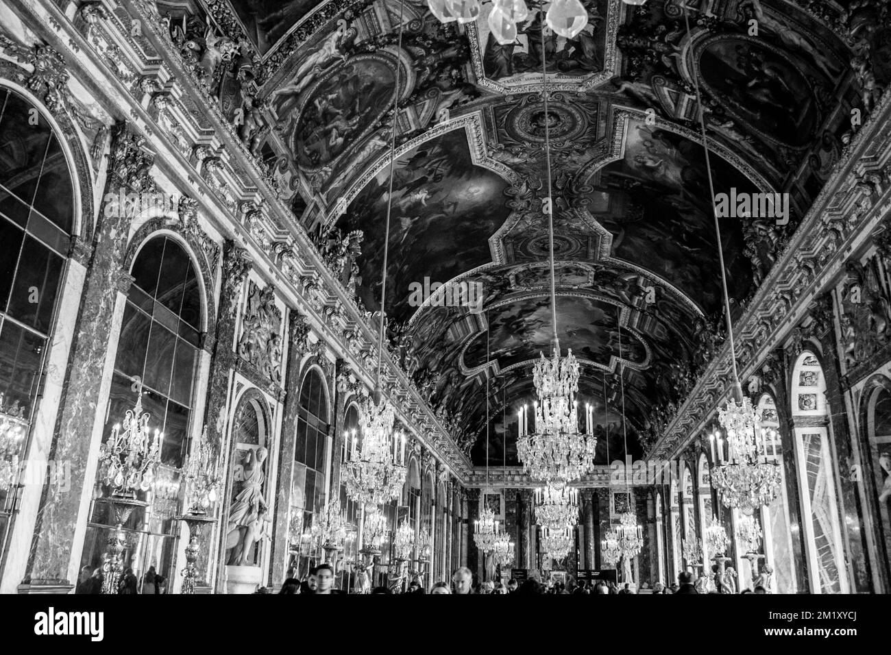A grayscale of the luxurious Palace of Versailles interior with wall ornaments and candle chandeliers Stock Photo