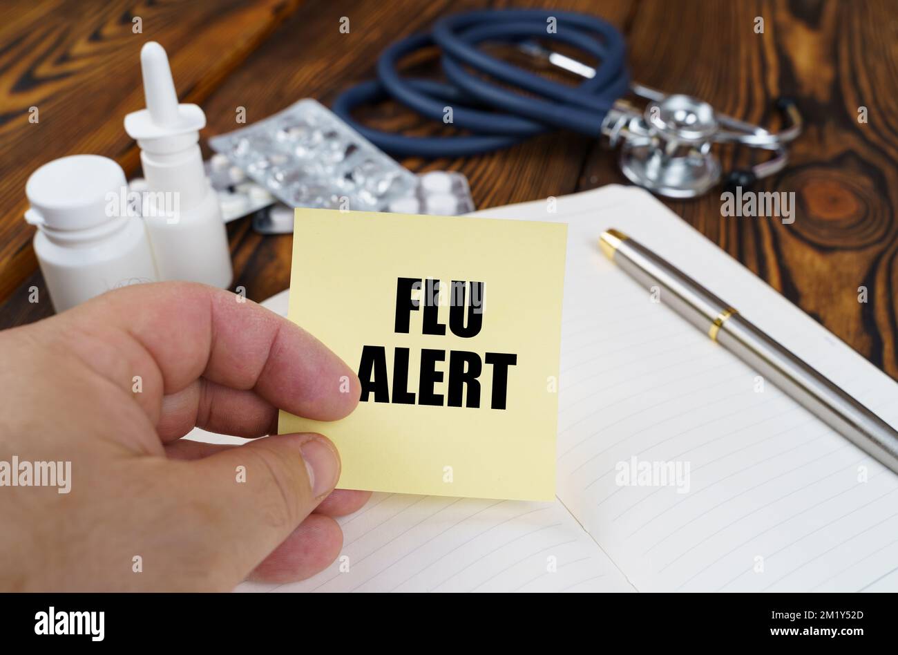 Medical concept. On the table is a notebook, medicines and a stethoscope, in the hands of a sticker with the inscription - Flu alert Stock Photo