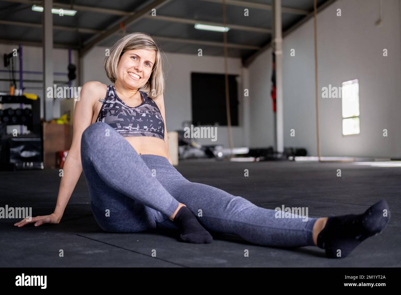 Close up of active fitness woman taking off dirty socks while sitting on  floor. Stock Photo