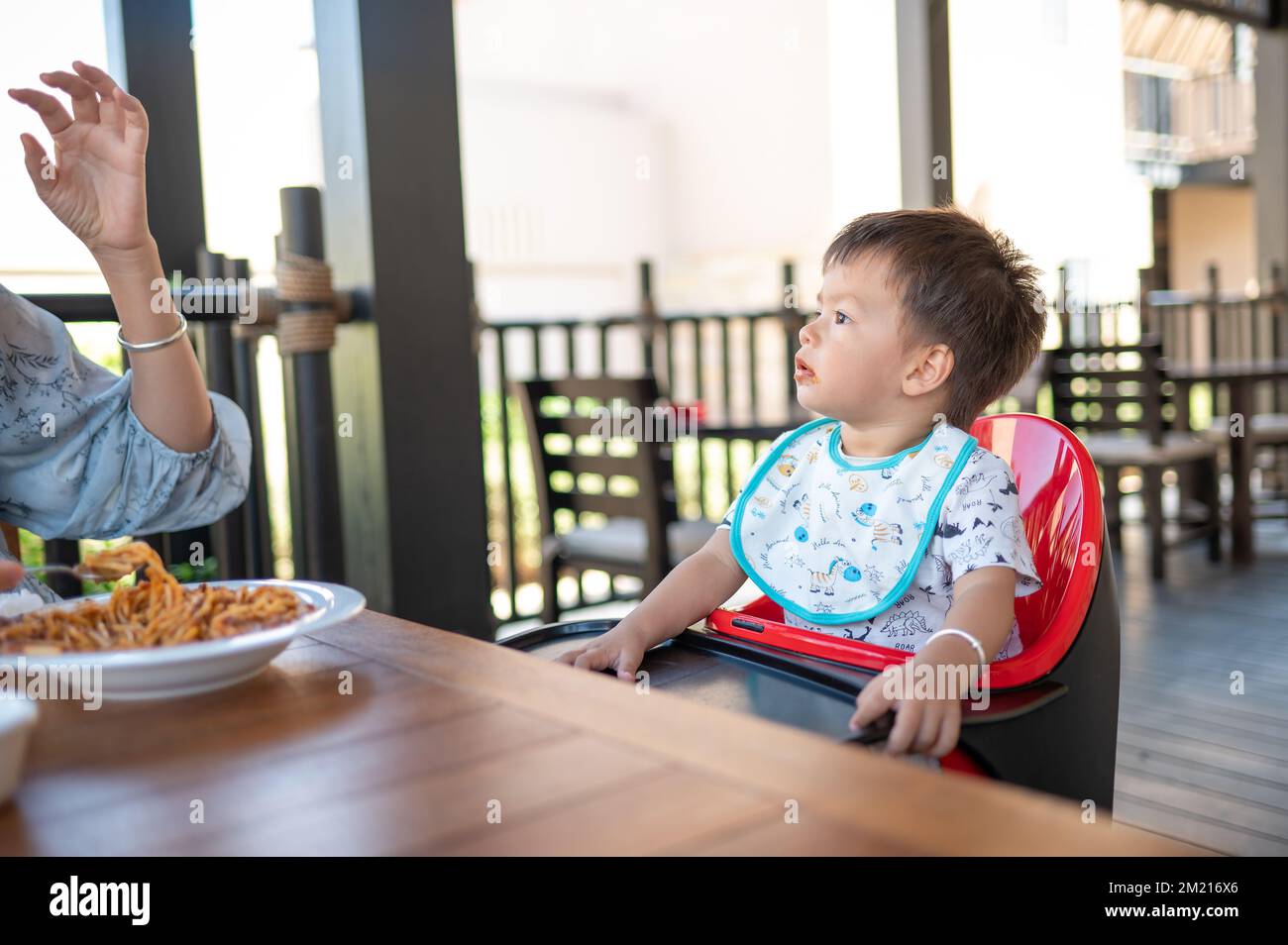 Toddler sitting on a high chair in the restaurant during a meal