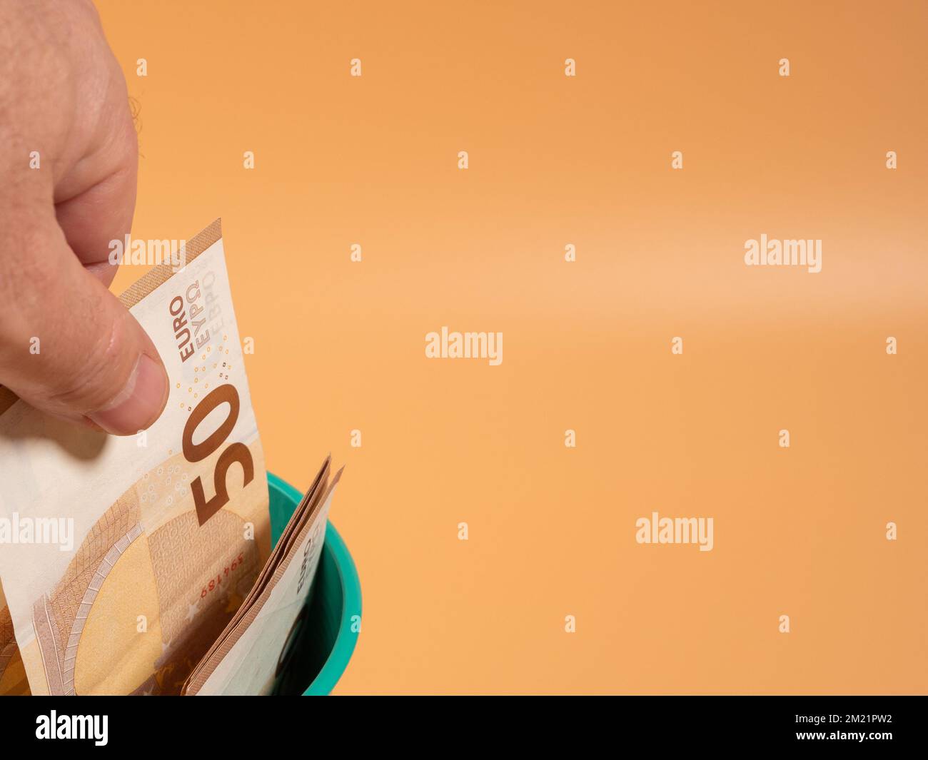Money in the trash can on an orange background. Euros in the trash