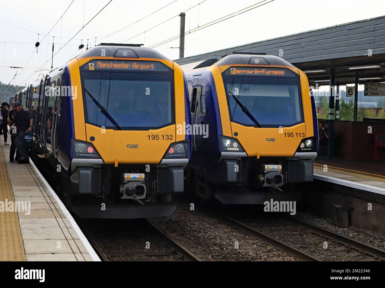 Two Northern DMU trains call at Wigan North Western in September 2022, one on a Barrow to Manchester Airport service and one going in the opposite way Stock Photo