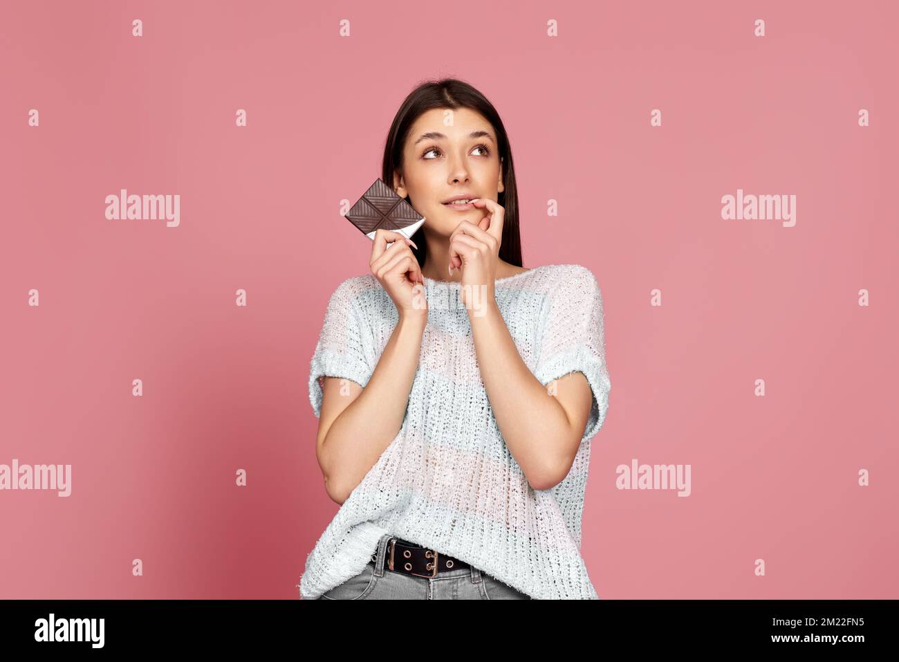 young woman in sweater holding chocolate bar Stock Photo