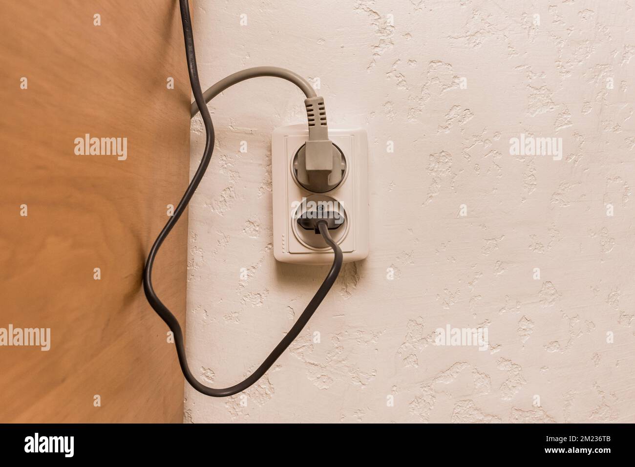 Two plugs in the socket in a modern interior. Safe connection of