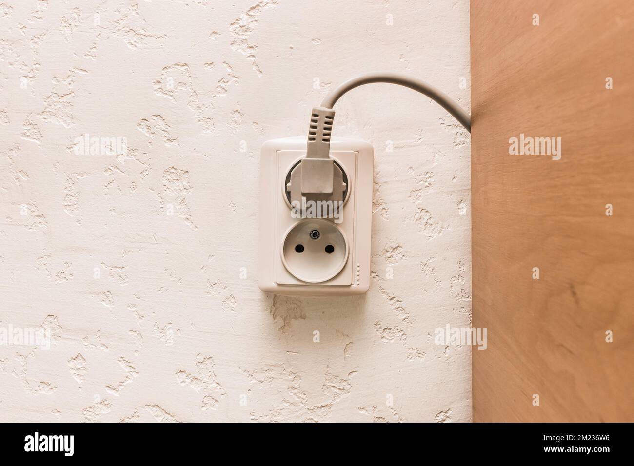 Two plugs in the socket in a modern interior. Safe connection of