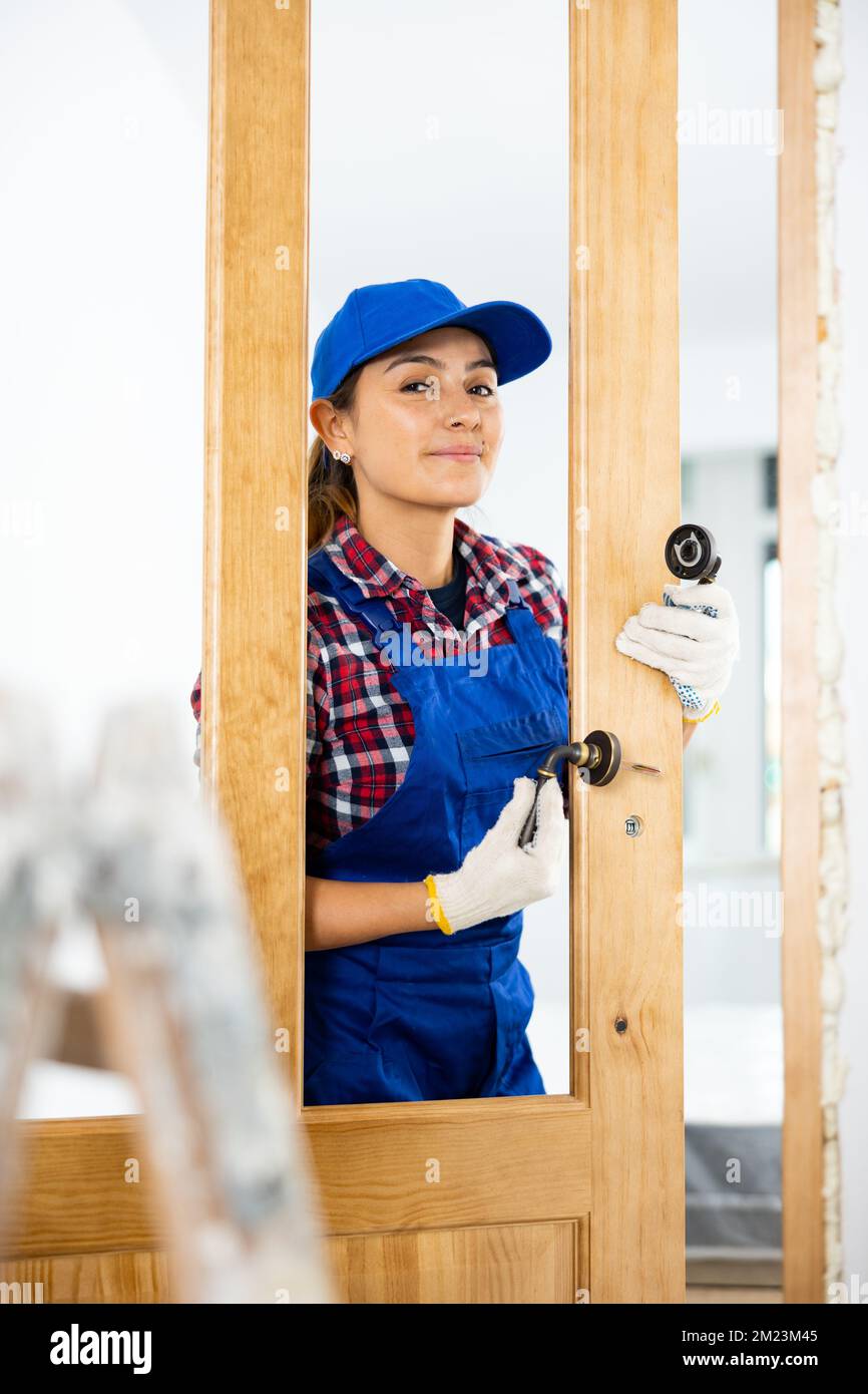 View of Professional female door installer trying on door handles for ...