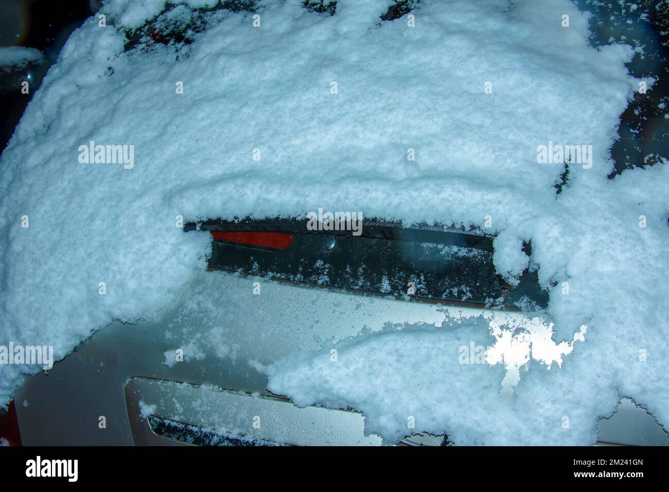 Frozen car trunk lid covered with ice and snow on a winter day. Close