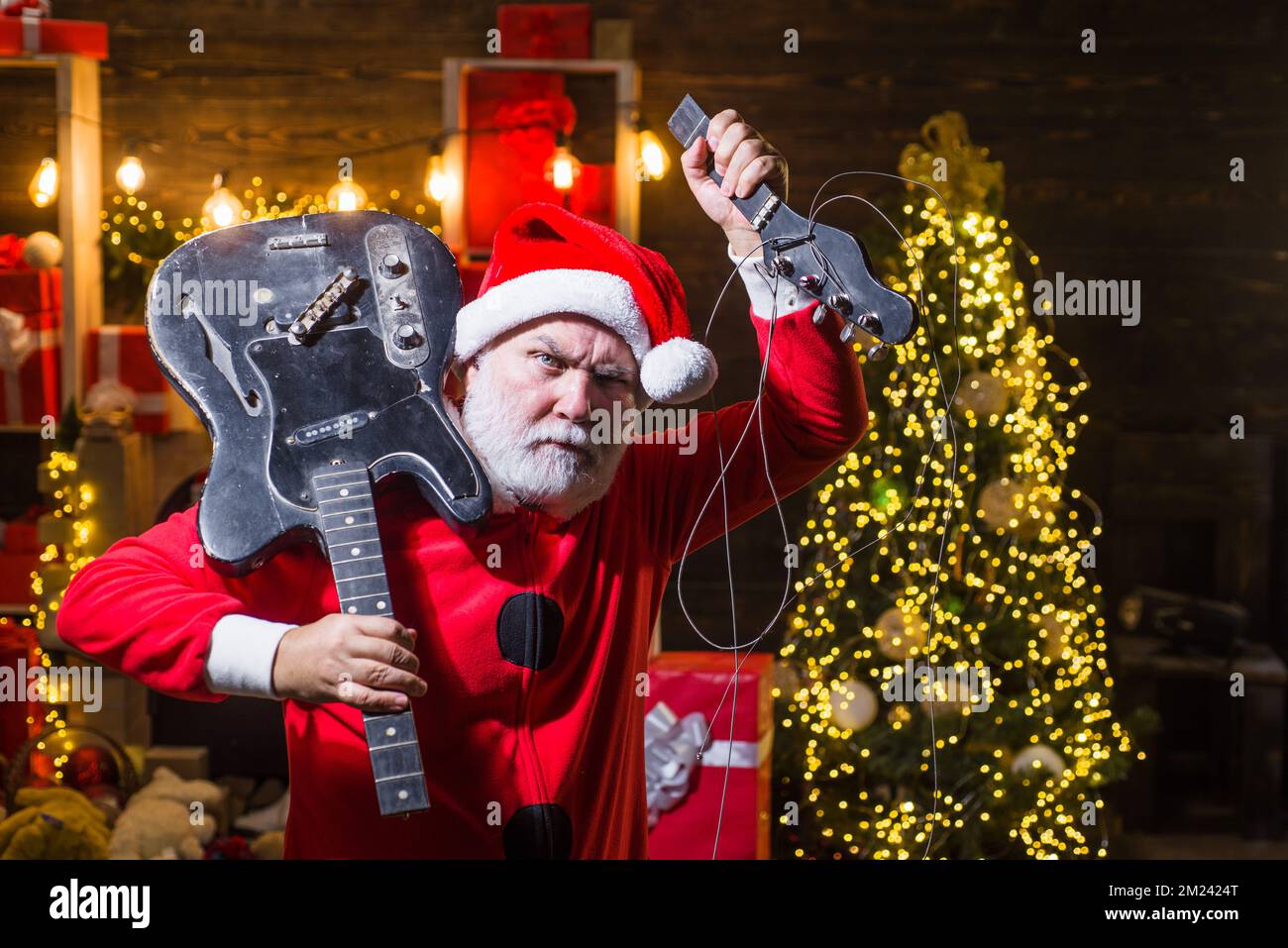 Merry Christmas. New Year party. Bearded Santa Claus rock musician with broken electric guitar. Stock Photo