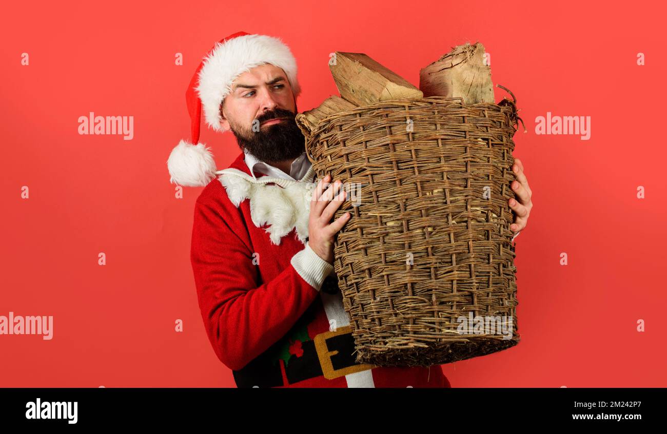 Merry Christmas. Santa Claus with wicker basket of chopped firewood for fireplace. Holiday vacation Stock Photo