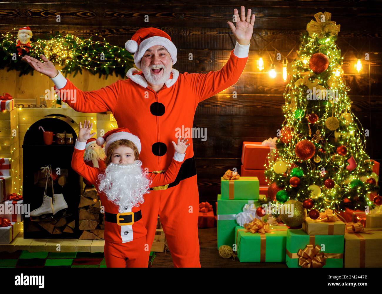 Santa Claus and child boy at home near Christmas tree with gift box. Happy new year. Family holiday Stock Photo