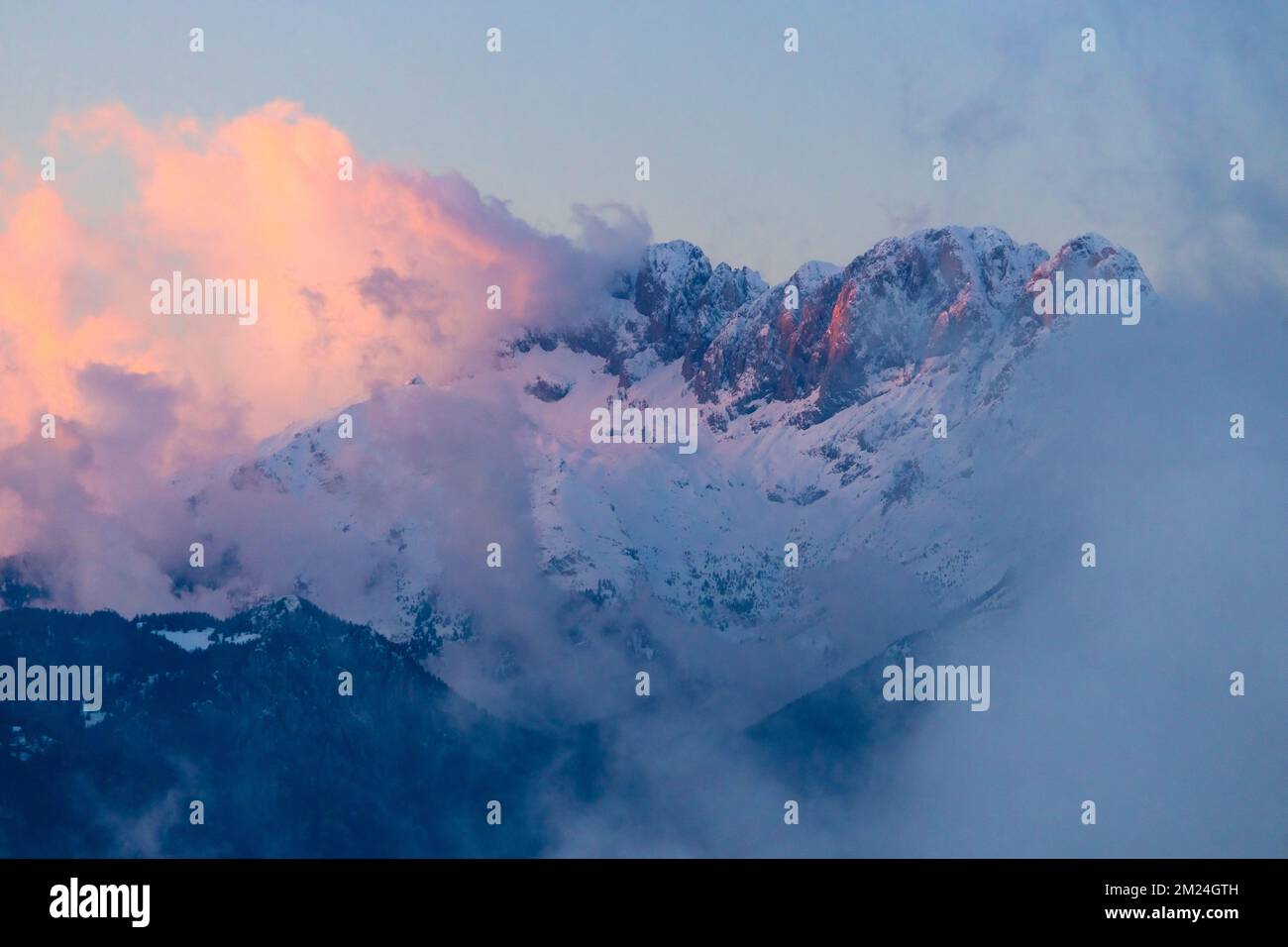 View of the the Presolana mountain between the clouds on a winter sunset. Val Seriana, Castione della Presolana, Bergamo district, Lombardy, Italy. Stock Photo