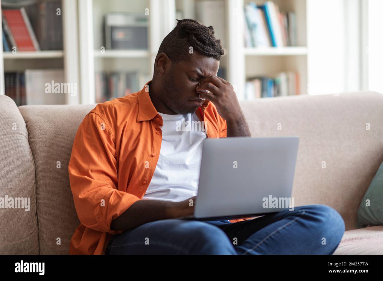 Young upset black man using laptop at home Stock Photo