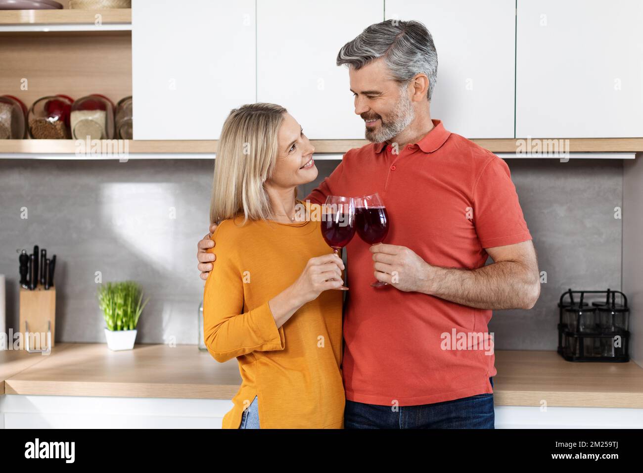 Romantic middle aged husband and wife drinking wine at home Stock Photo