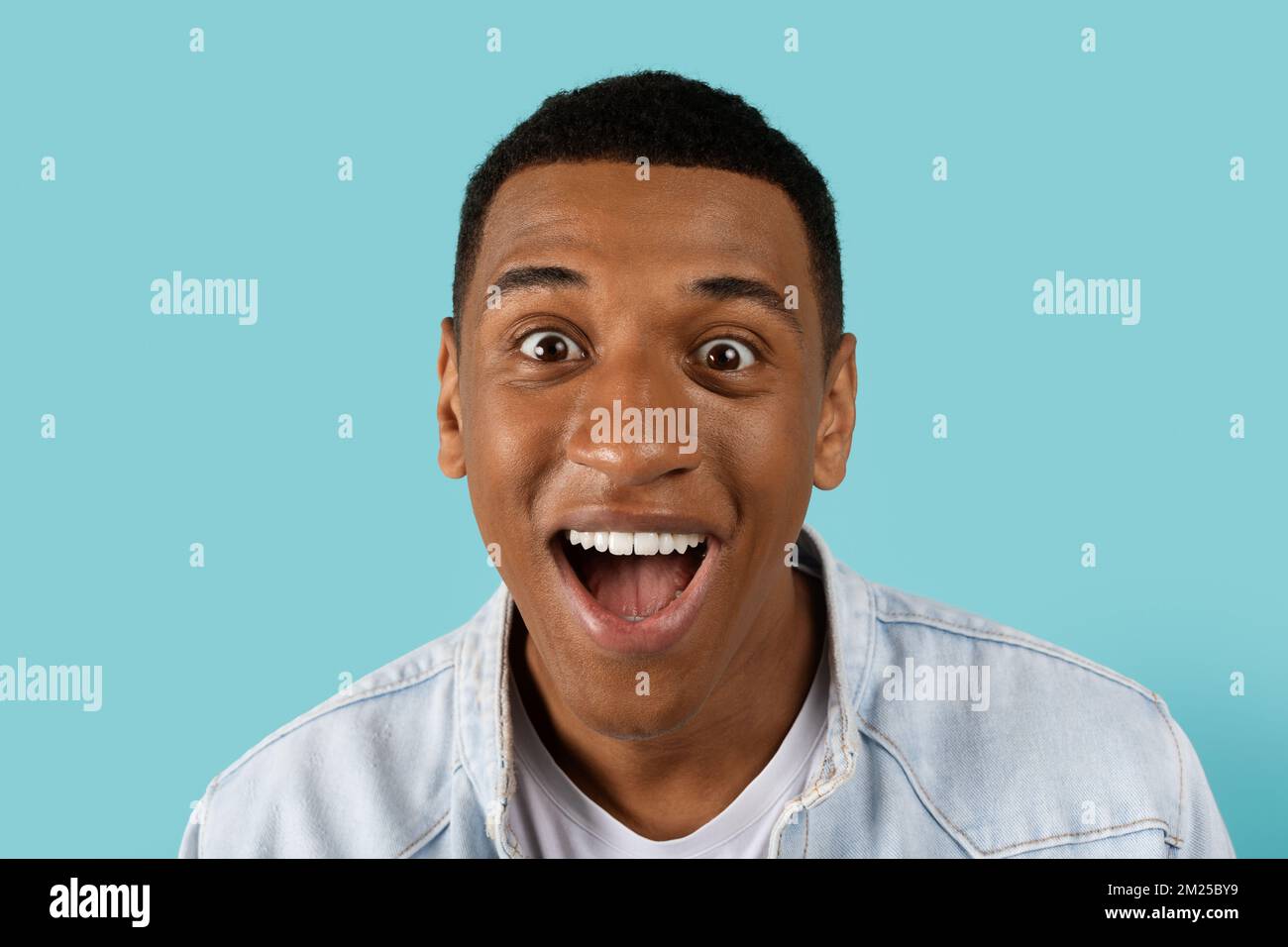 Cheerful funny young african american man with open mouth scream, look