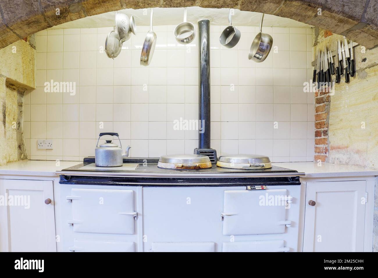 Country farmhouse kitchen with cast iron oven and hanging pans. Stock Photo