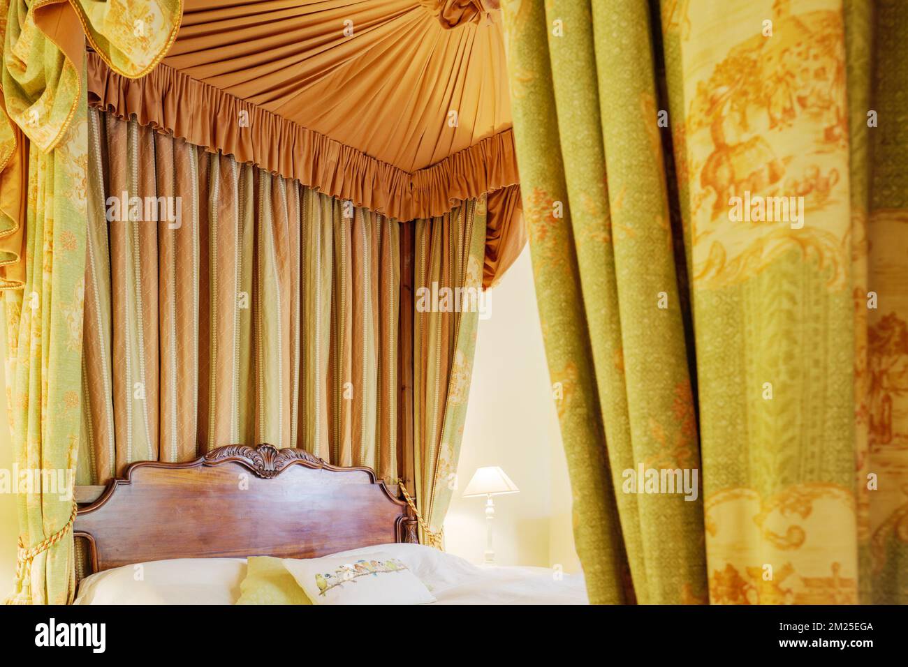 Traditional wooden four poster bed with drapes and curtains Stock Photo
