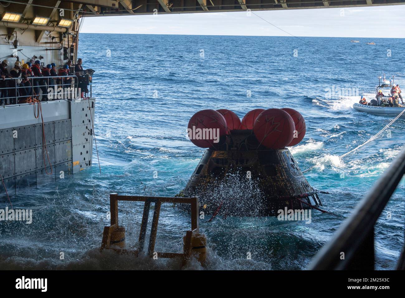 Pacific Ocean, United States of America. 11 December, 2022. U.S. Navy recovery teams use a line load attenuating mechanism assembly to pull the unmanned NASA Orion spacecraft from the Artemis I mission into the well deck of the USS Portland following splashdown in the Pacific Ocean, December 11, 2022 off the coast of Baja California. The unmanned Orion spacecraft spent 25 days in space during a test journey to the moon. Credit: MC2 Devin Kates/U.S. Navy/Alamy Live News Stock Photo