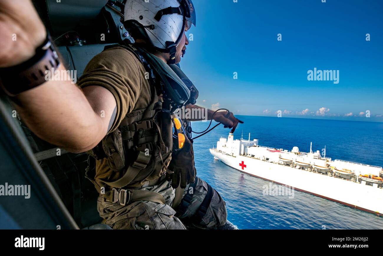 Jeremie, Haiti. 12th Dec, 2022. Naval Aircrewman (Helicopter) 2nd Class Bryce Batiancela, assigned to the 'Chargers' of Helicopter Sea Combat Squadron (HSC) 26, Detachment 3, attached to the hospital ship USNS Comfort (T-AH 20), monitors the helicopter's distance from the ship during flight operations off the coast of Jeremie, Haiti, Dec. 12, 2022. Comfort is currently deployed in support of Continuing Promise 2022, a humanitarian assistance and goodwill mission conducting direct medical care, expeditionary veterinary care, and subject matter expert exchanges with five partner nations in Stock Photo