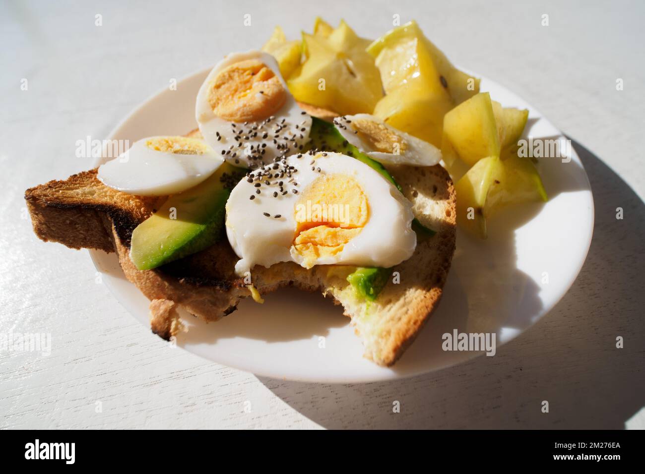 Sliced avocado and egg on toasted bread with bite. Close-up. Stock Photo