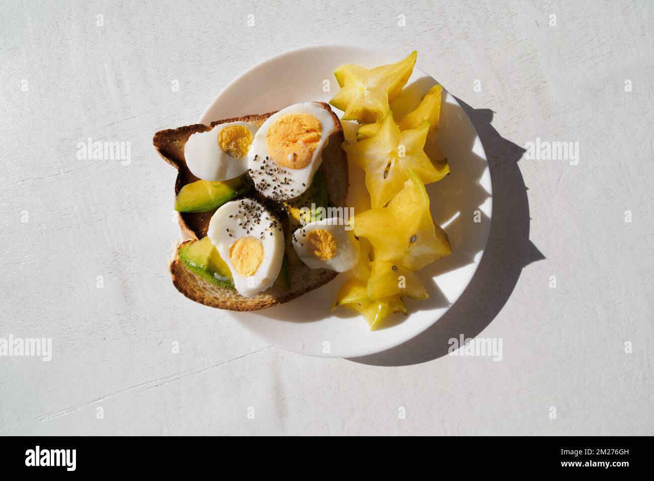 Sliced avocado and egg on toasted bread with carambola for healthy breakfast.  Stock Photo