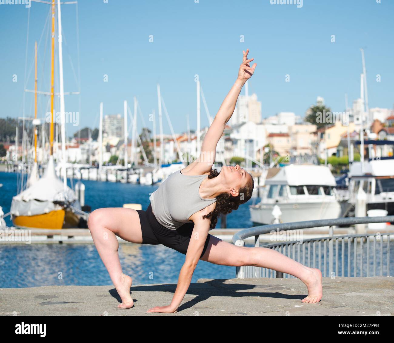 Yoga pose outdoors at a marina against a blue sky Stock Photo