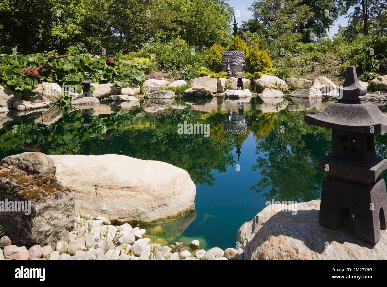 Pond with Asian ornamental sculptures in Zen garden at Route des Gerbes d'Angelica garden in spring, Mirabel, Quebec, Laurentians, Canada. Stock Photo