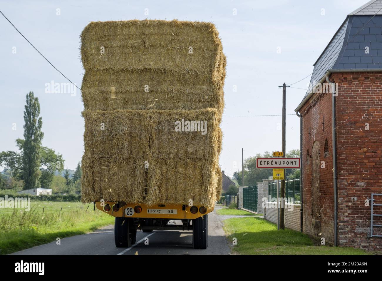 Tractor loaded with bales of straw on a countryside road | Tracteur charge de bottes de paille sur une route de campagne 29/08/2017 Stock Photo