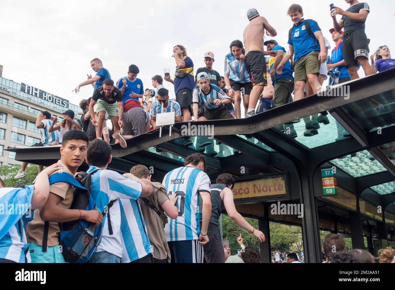 Argentine fans climb onto top of bus shelter on 9th July Avenue, Buenos Aires, Argentina to celebrate the national team reaching the final of the 2022 Stock Photo