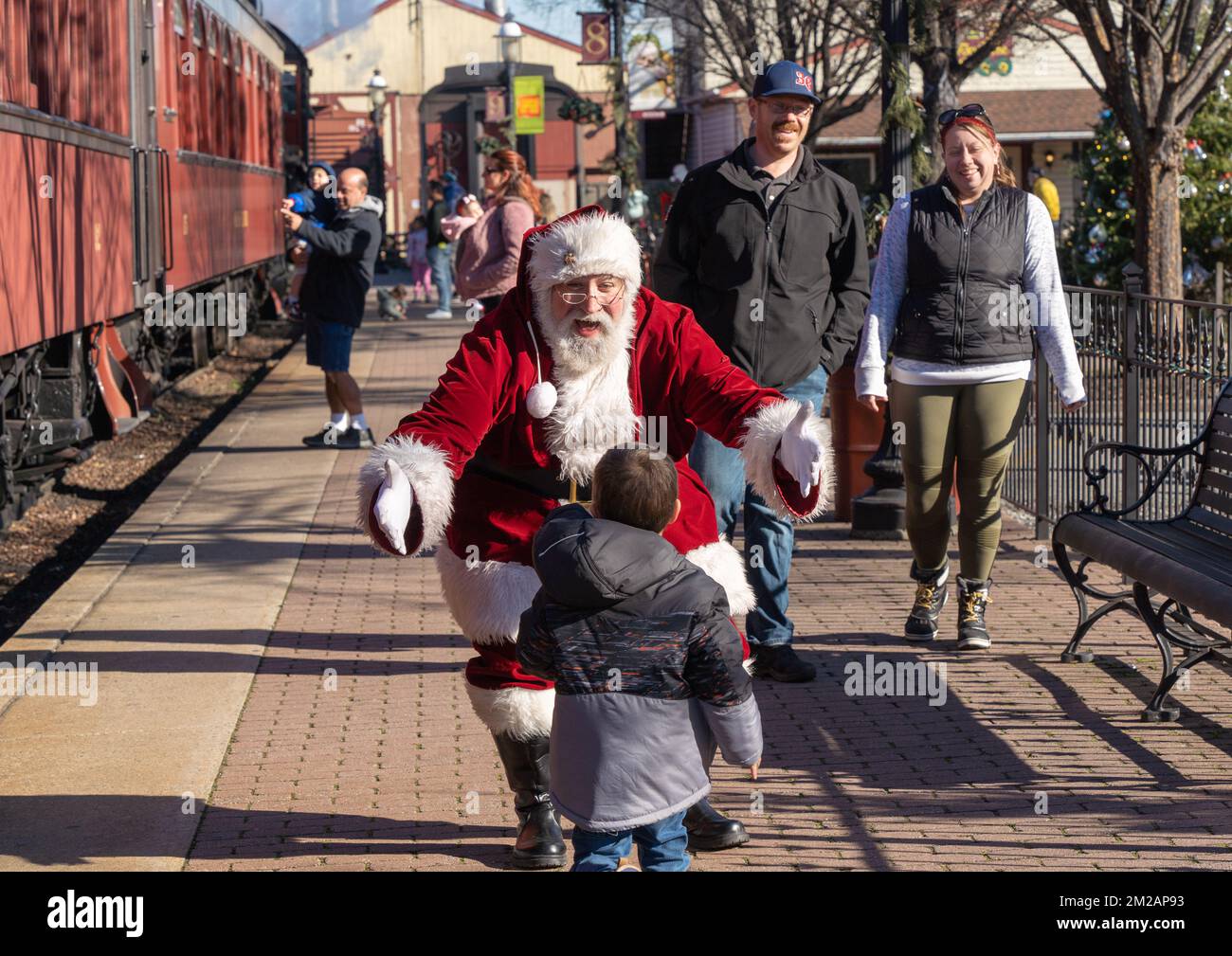 December 11, 2022: Strasburg, Pennsylvania: Parents watch as Senior Gentlemen dressed as Santa Claus greets small child at Strasburg Railroad Christma Stock Photo