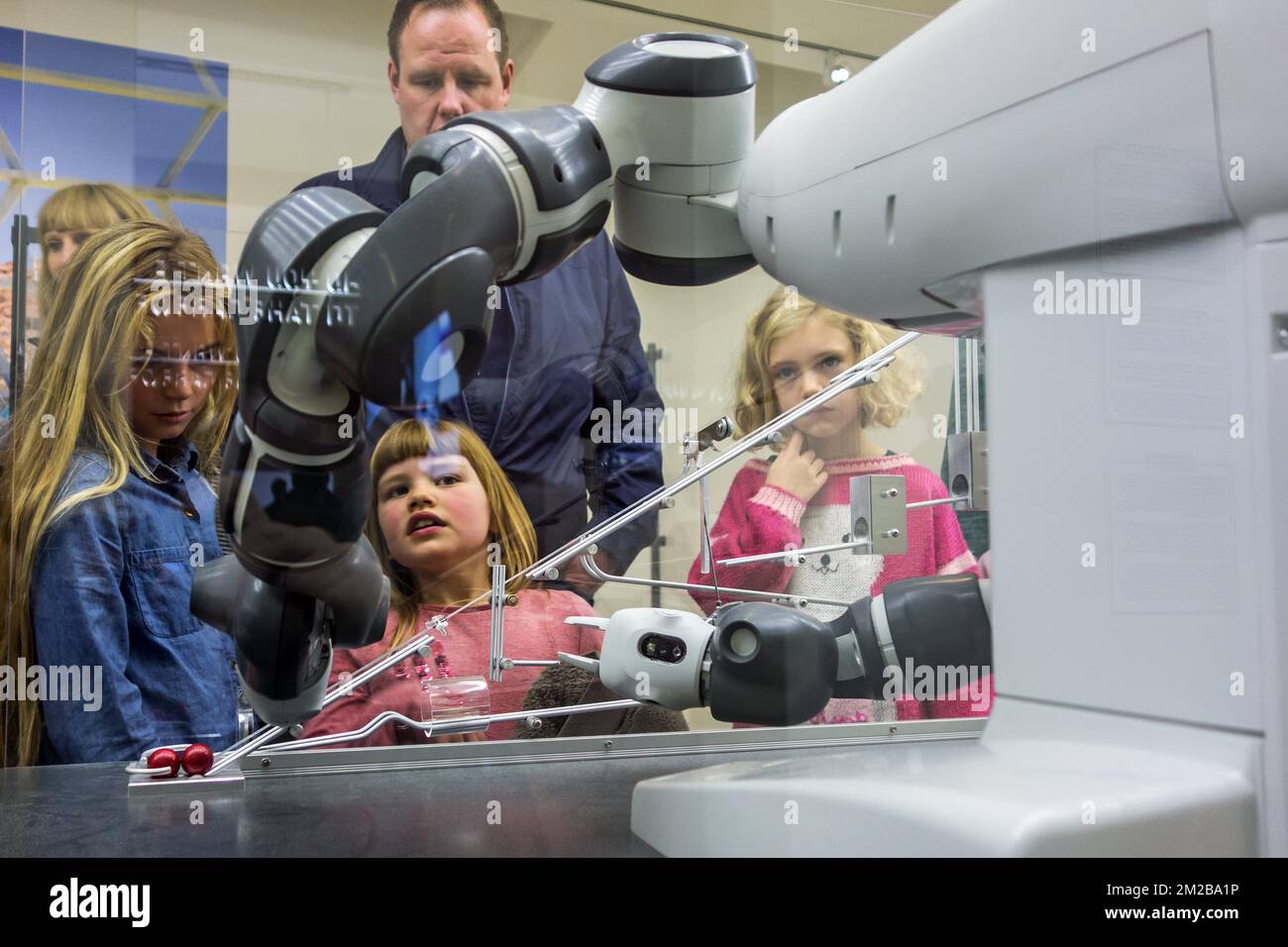 Curious children looking at demonstration with industrial robot arms at exposition about robotics and artificial intelligence / AI | Enfants regardent démonstration d'un robot industriel pendant exposition concernant la robotique et intelligence artificielle 26/11/2017 Stock Photo