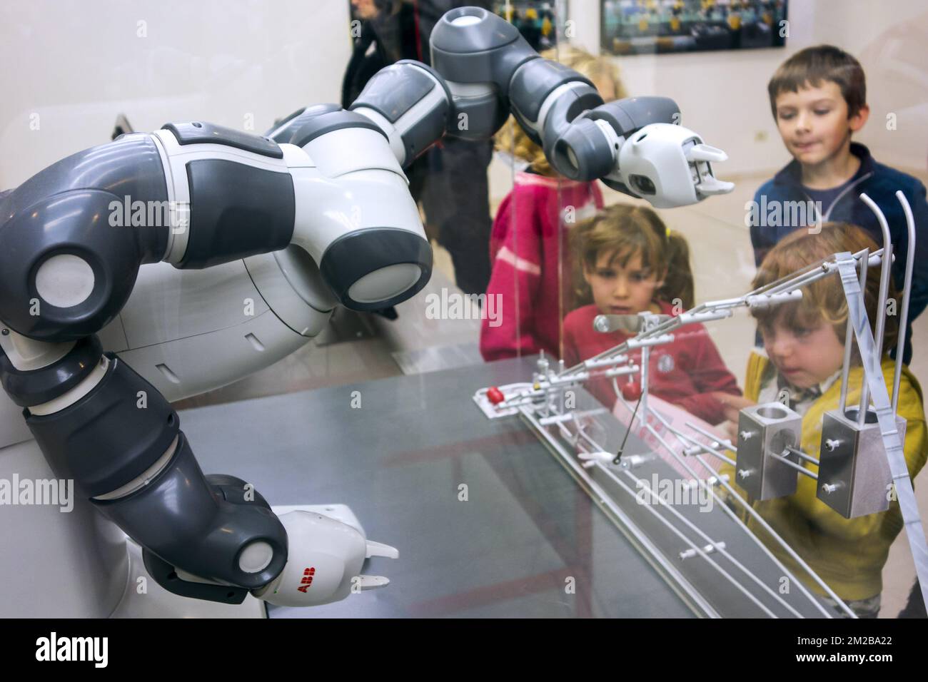 Curious children looking at demonstration with industrial robot arms at exposition about robotics and artificial intelligence / AI | Enfants regardent démonstration d'un robot industriel pendant exposition concernant la robotique et intelligence artificielle 26/11/2017 Stock Photo