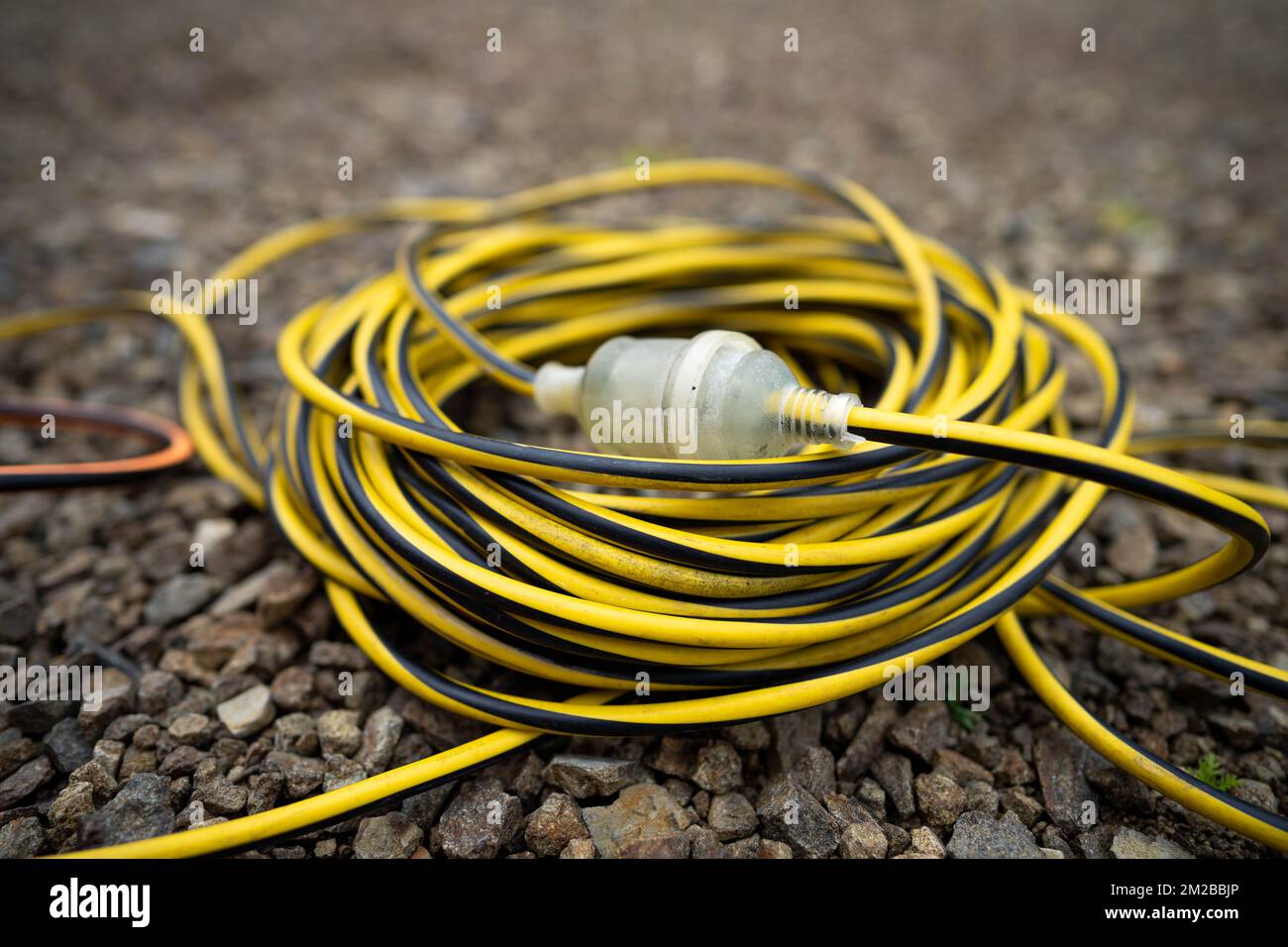 extension cord wrapped up on the ground. extension lead, power lead on