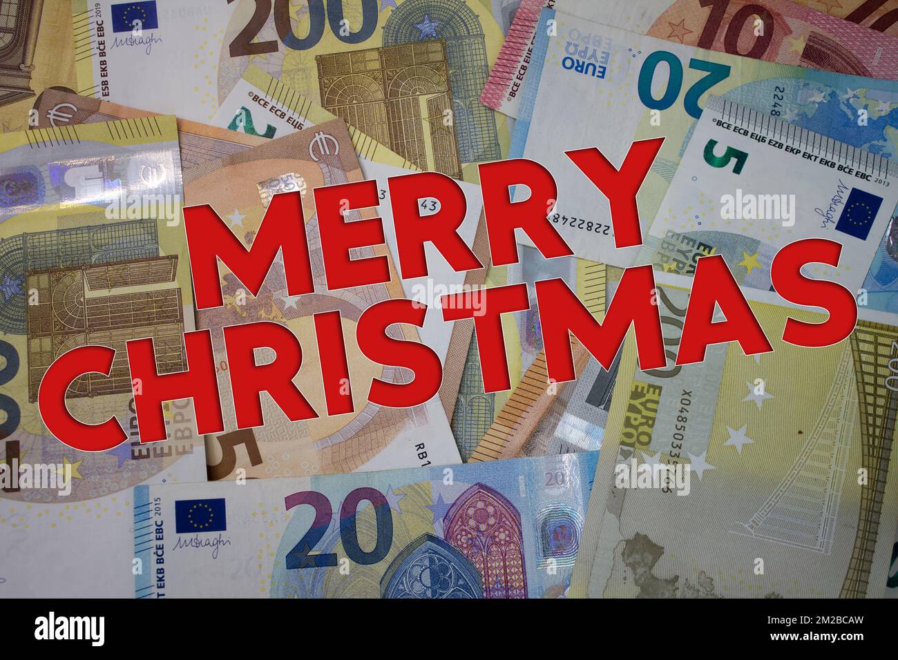 Merry Christmas word with money. Paper currency background with different banknotes. Stock Photo