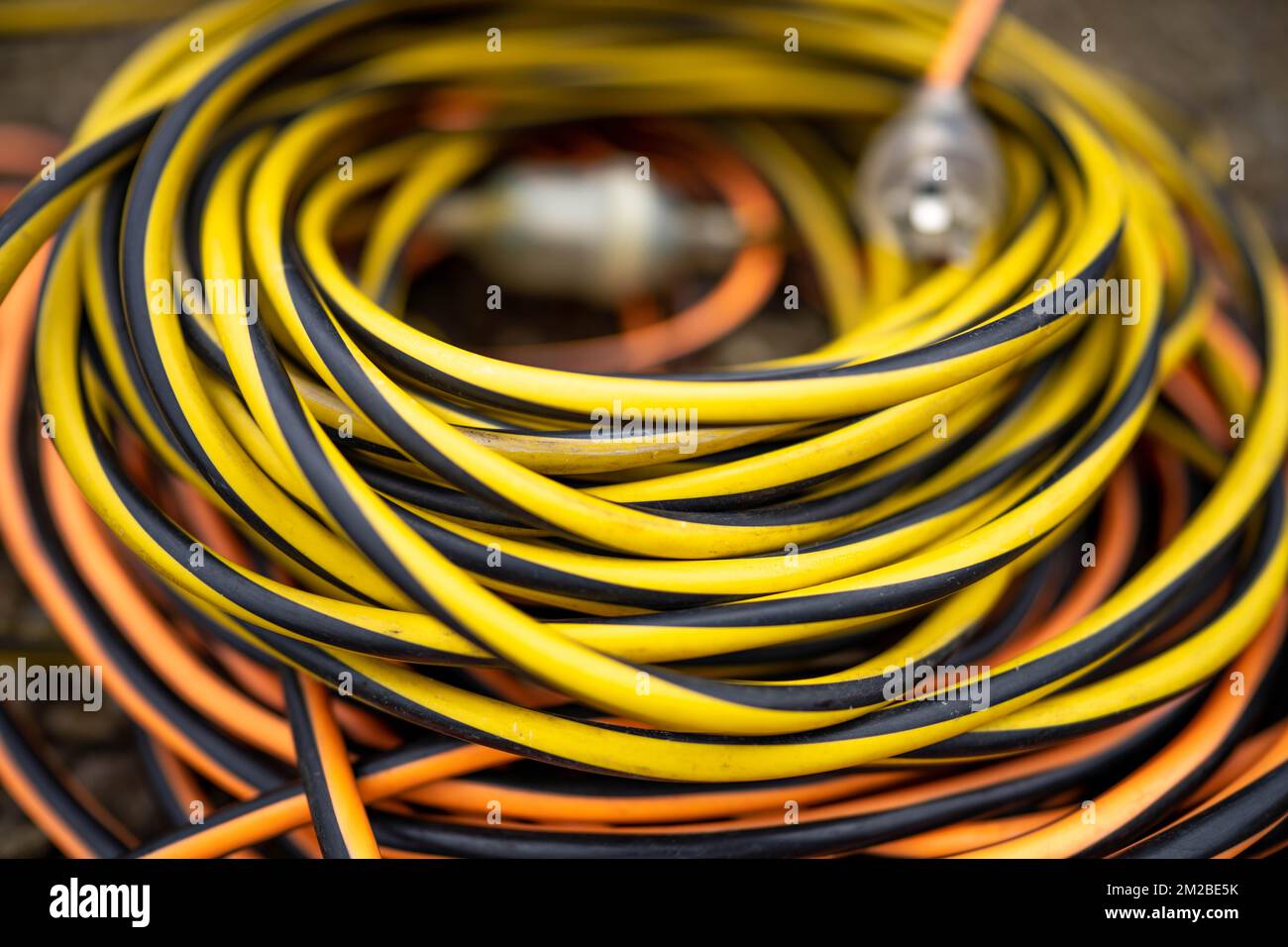 extension cord wrapped up on the ground. extension lead, power lead on