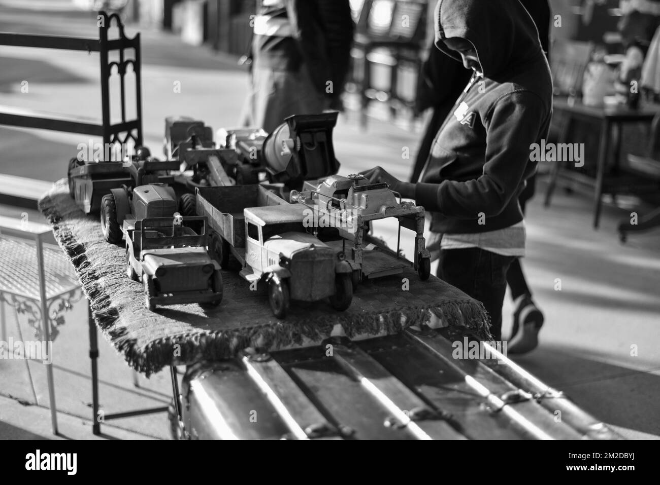 Candid photo of a little boy looking at vintage toy cars and trucks Stock Photo