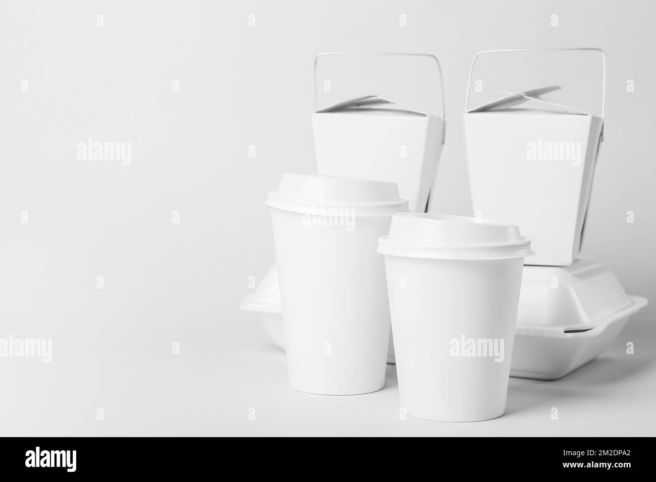 Paper cups and different food containers on light background Stock