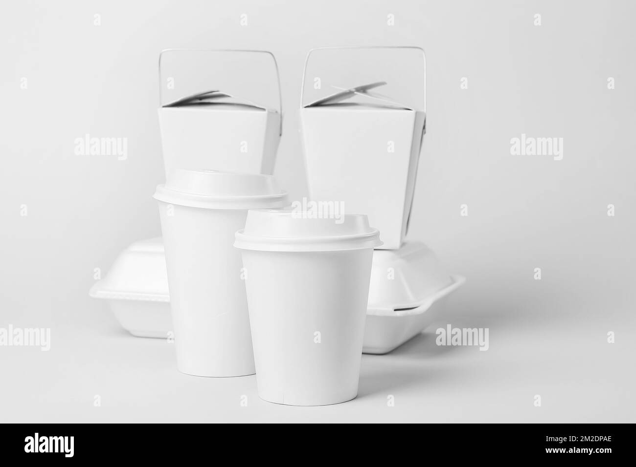 Paper cups and different food containers on light background Stock