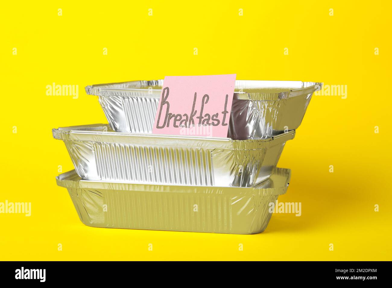 Stack of takeaway boxes and sticky note with word BREAKFAST on color background Stock Photo