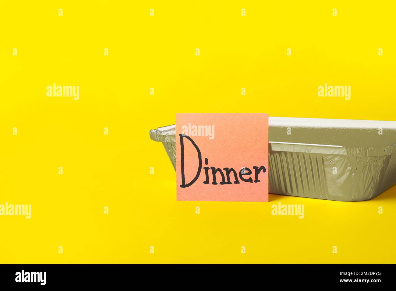 Takeaway box and sticky note with word DINNER on color background Stock Photo
