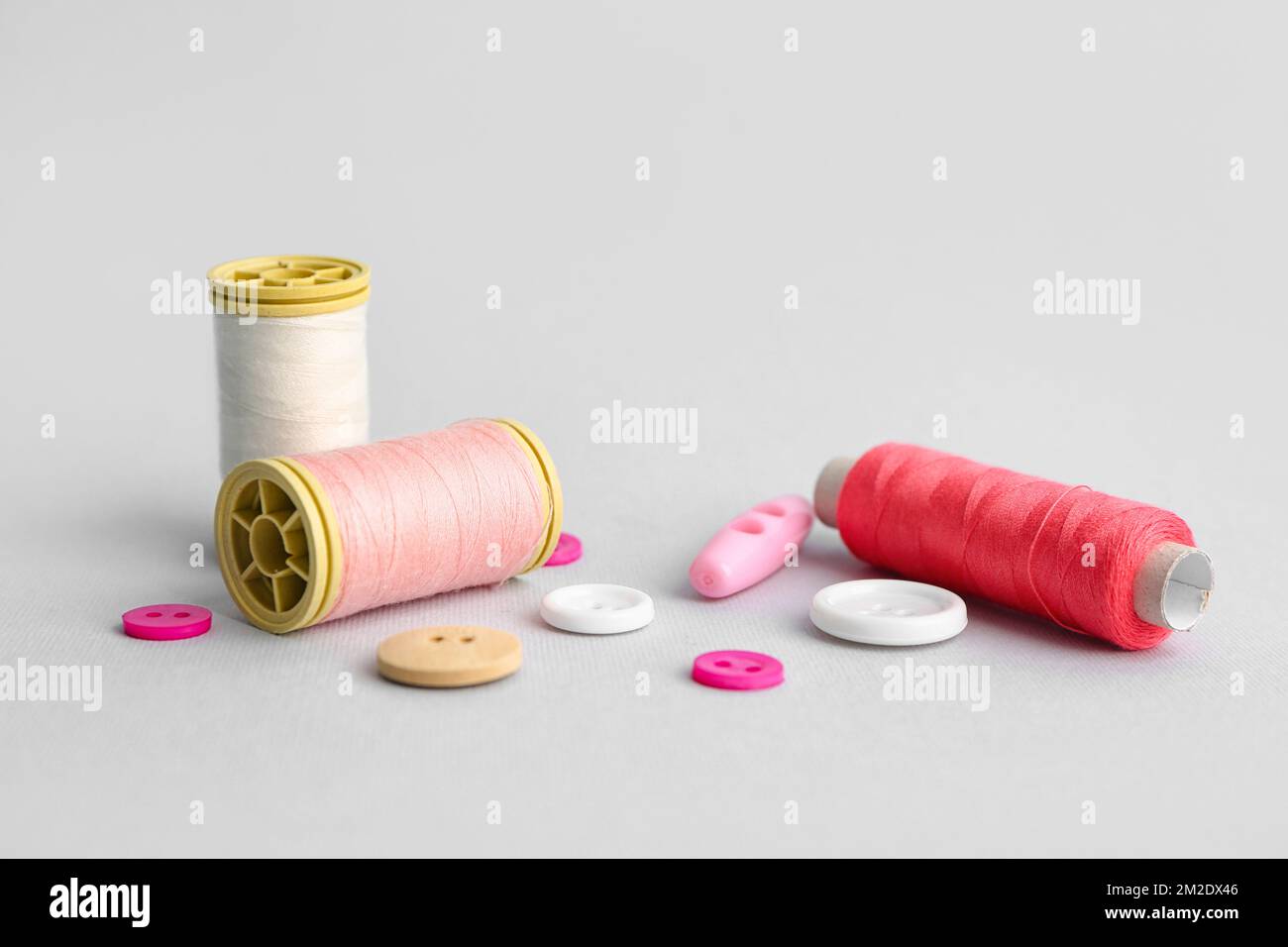 Thread spools and different buttons on grey background Stock Photo