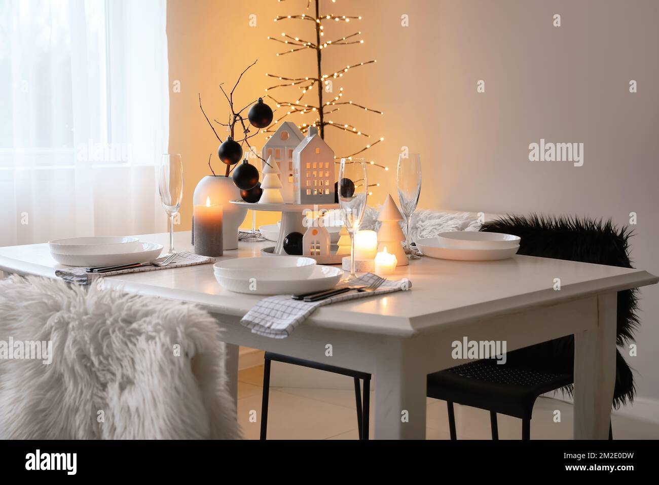 Table setting with burning candles and Christmas balls in dining room ...