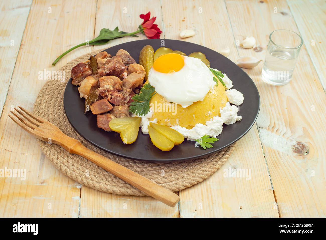 Romanian traditional dish  'Tochitura moldoveneasca', Recipe made with pork meat and sausages, Cheese, egg and ' mamaliga', on a black plate Stock Photo