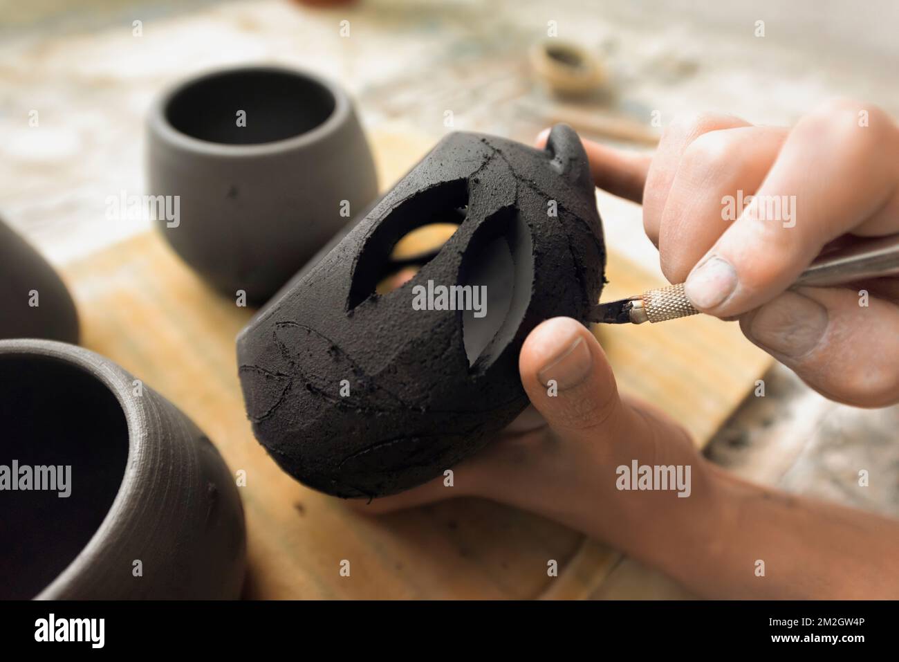 The master of sculpting pottery working in a studio. Cuts holes in